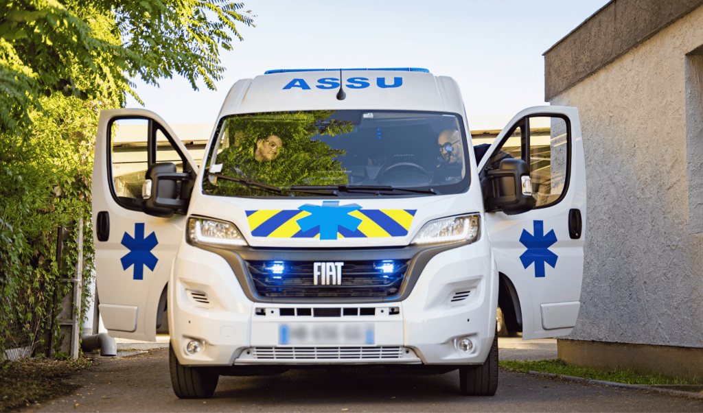 Ambulance Fiat Dax Assistance de face, gyrophares bleus allumés et portes ouvertes, prête pour un transport sanitaire vers Dax, Bayonne ou Mont-de-Marsan
