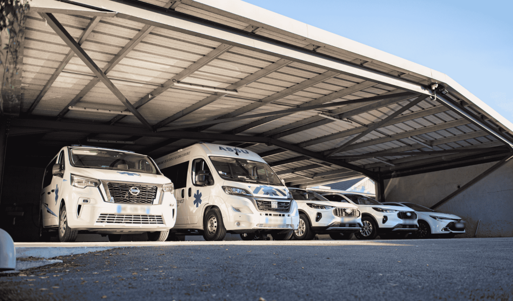 Parc de véhicules sanitaires Dax Assistance sous hangar : VSL Nissan, ambulance Fiat et berlines pour les transports à Dax, Bayonne et Mont-de-Marsan